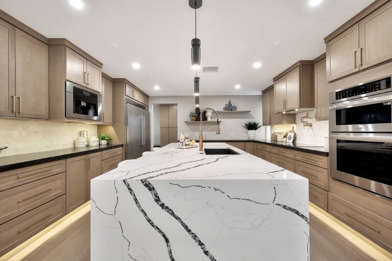 Remodeled kitchen with taupe cabinets and a white veined island countertop